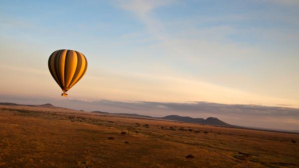 hot air balloon floating over the arid Serengeti valley, Tanzania